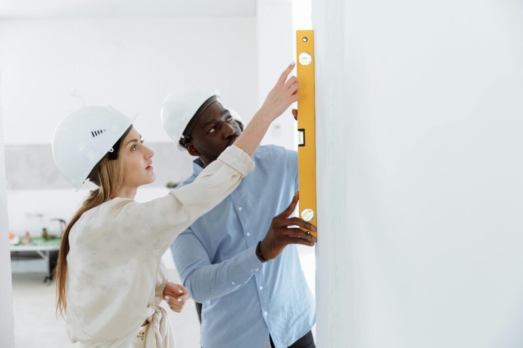 Two construction workers using a level tool on an indoor wall for accuracy.